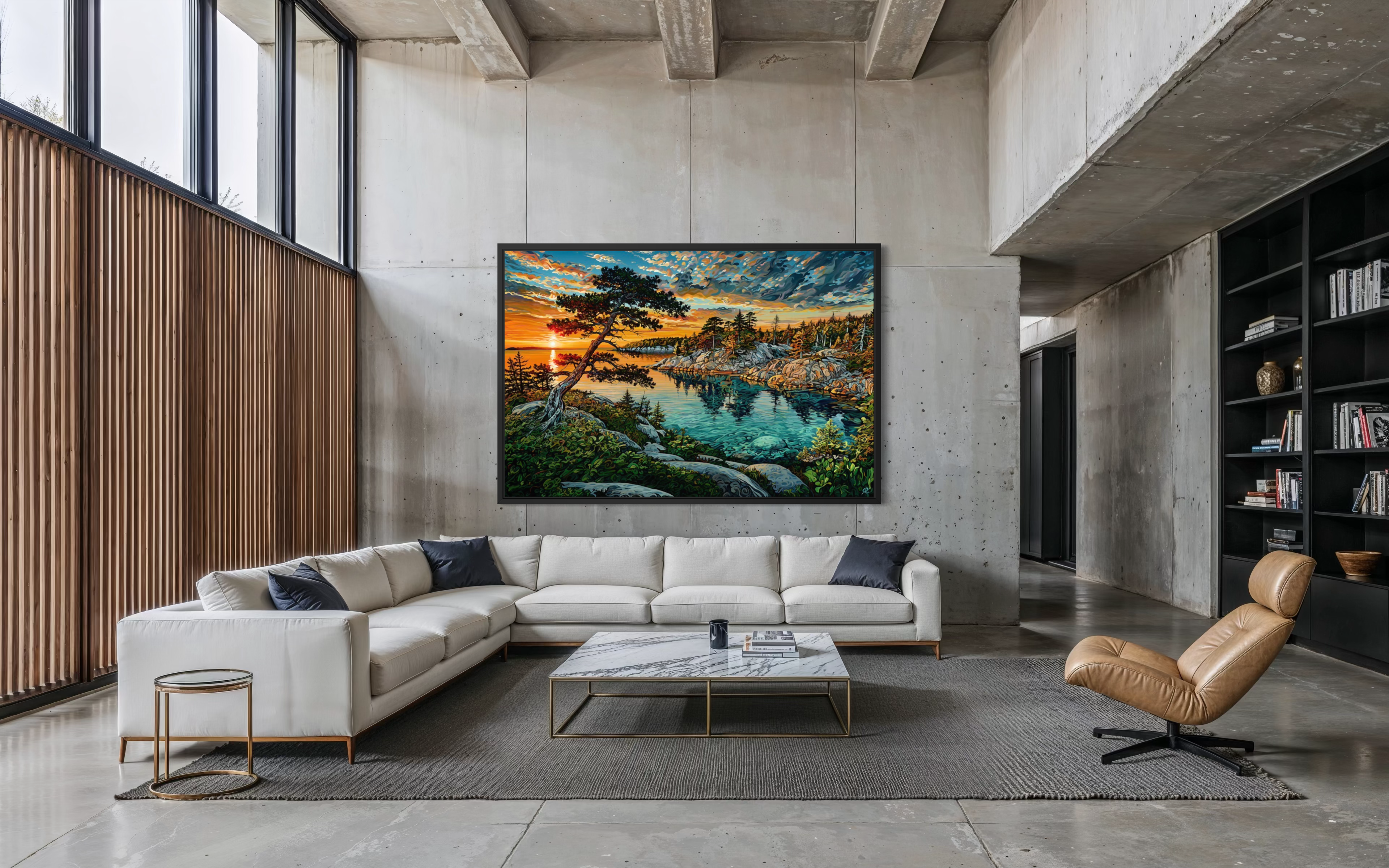 A large framed landscape art print depicting a vibrant sunset over a lake with pine trees, displayed on a concrete wall above a modern white sectional sofa in a stylish loft-style living room.