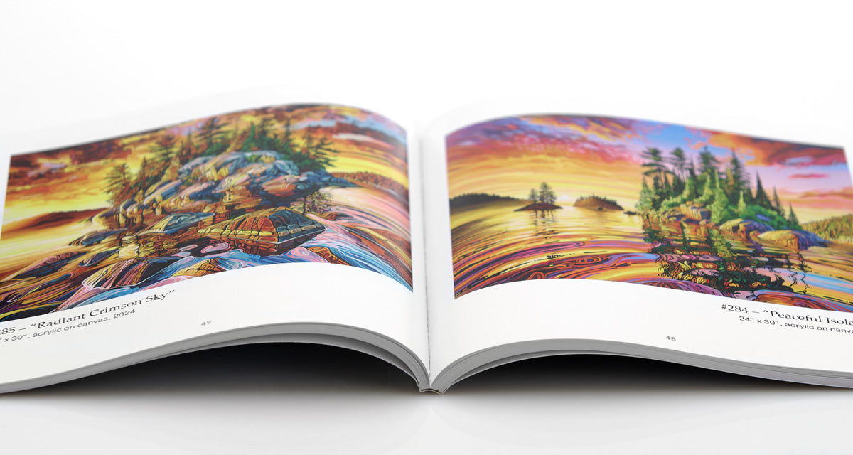The "Landscapes" Art Book by Jeff Dillon, an artist-signed edition, lies open on a white background, displaying vibrant Canadian lake and island scenes with colorful skies and reflections.