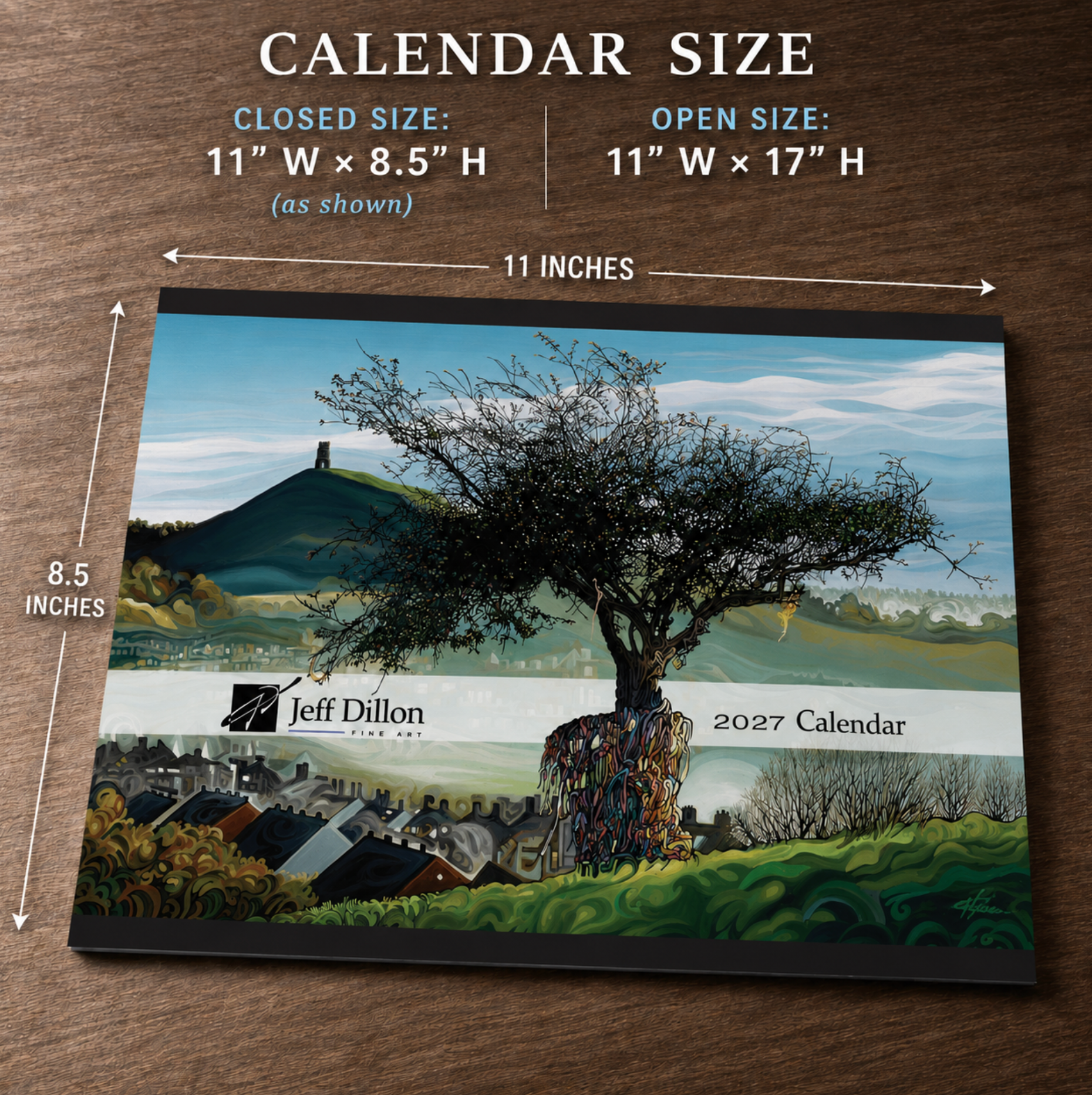 A 2027 Jeff Dillon calendar shown flat on a brown wood surface, with size callouts indicating closed size 11 x 8.5 inches and open size 11 x 17 inches.
